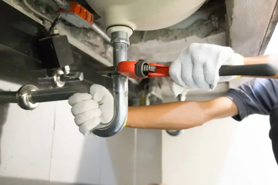 Plumber repairing a pipe under a sink